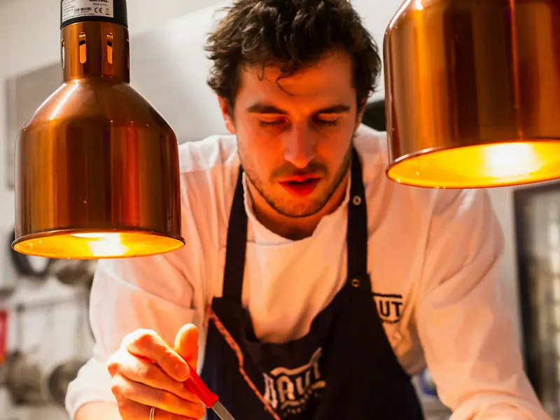 A chef in an apron plating food in a restaurant kitchen