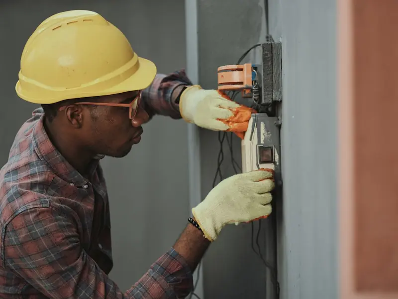 An electrician in a hard hat working on a panel