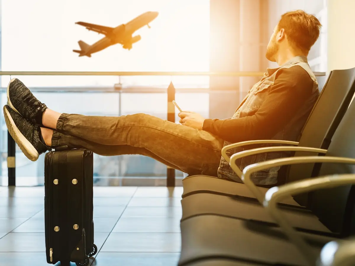 A traveller relaxing in an airport lounge as a plane takes off outside